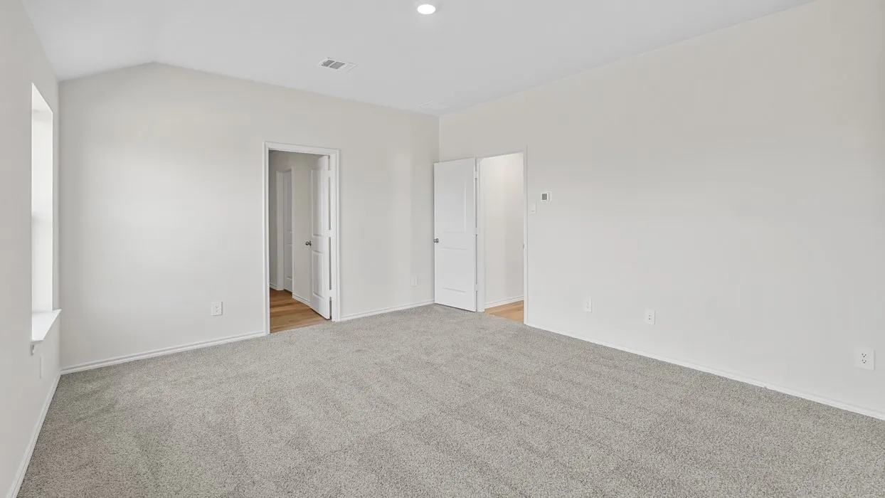 Spacious room featuring vaulted ceilings, light gray carpeting, neutral wall tones, a recessed light fixture, and two interior doorways