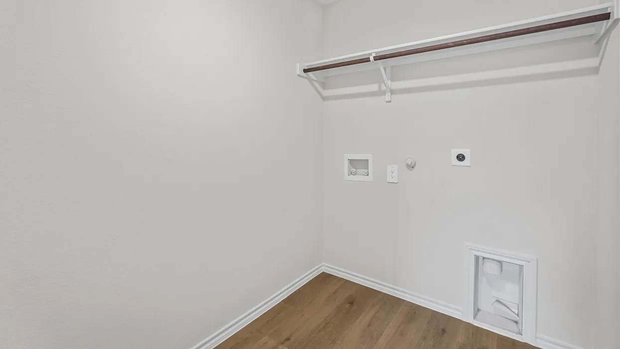 Utility area featuring wood-finish flooring, white baseboards, a built-in shelf, and a clothing rod