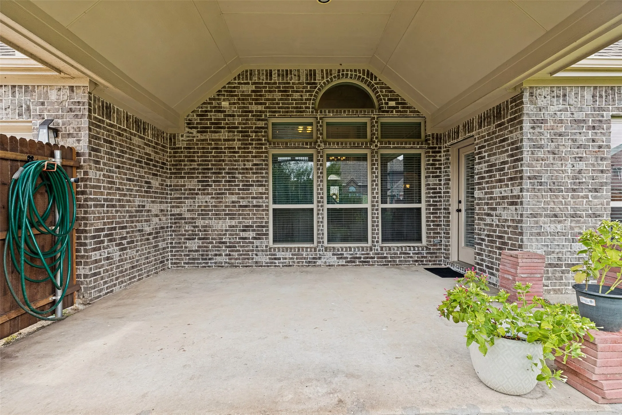 Covered patio featuring a concrete slab and brick exterior