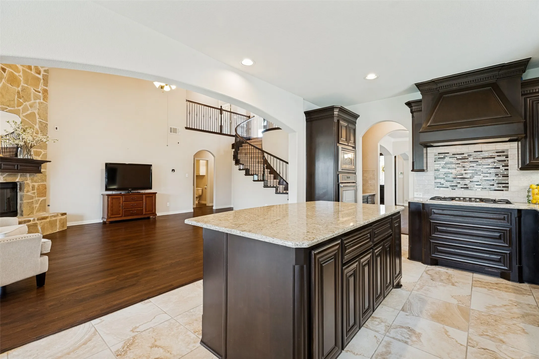 Kitchen island featuring a light-toned countertop, dark wood-finish cabinetry, and built-in stovetop