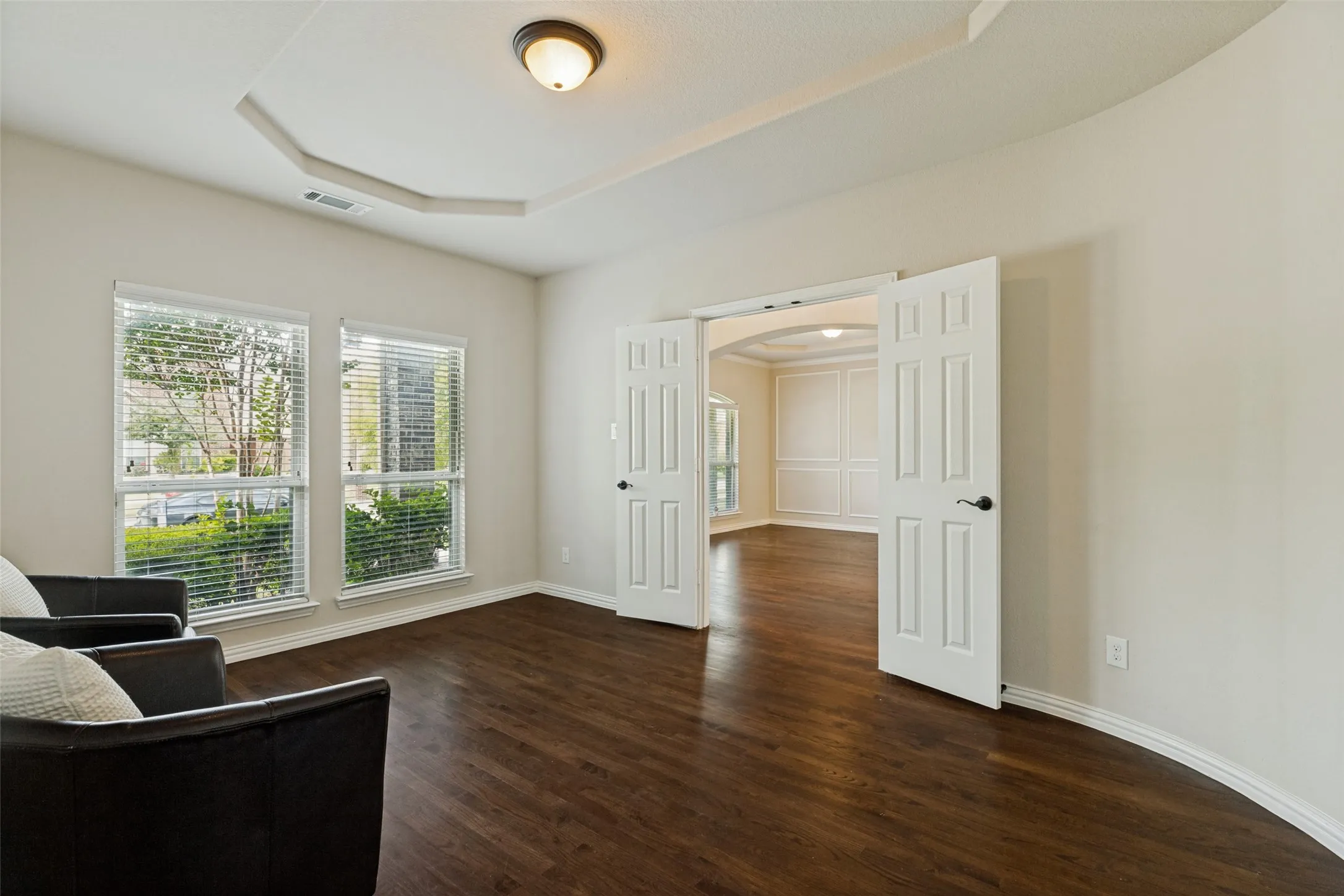 Sitting Room-Office-6th Bedroom off Entry featuring wood-finish flooring, two large windows, and a tray ceiling with a flush-mount light fixture