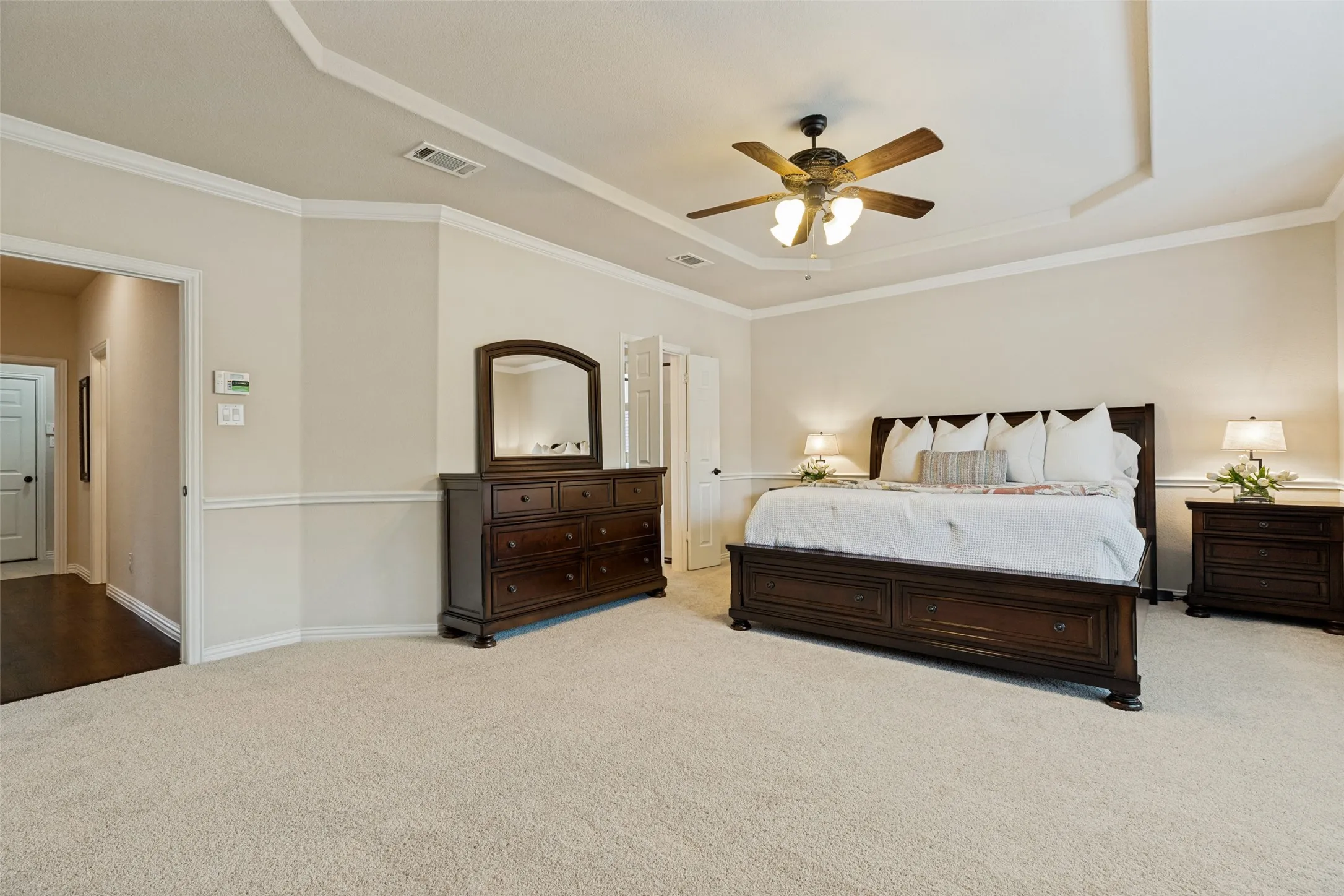 Spacious bedroom with tray ceiling, crown molding, and neutral wall tones