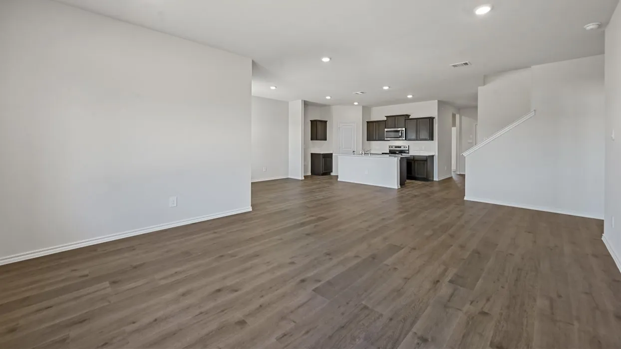 Open concept living area featuring wood-finish flooring, recessed lighting, white walls, and a kitchen with dark cabinetry and stainless steel appliances
