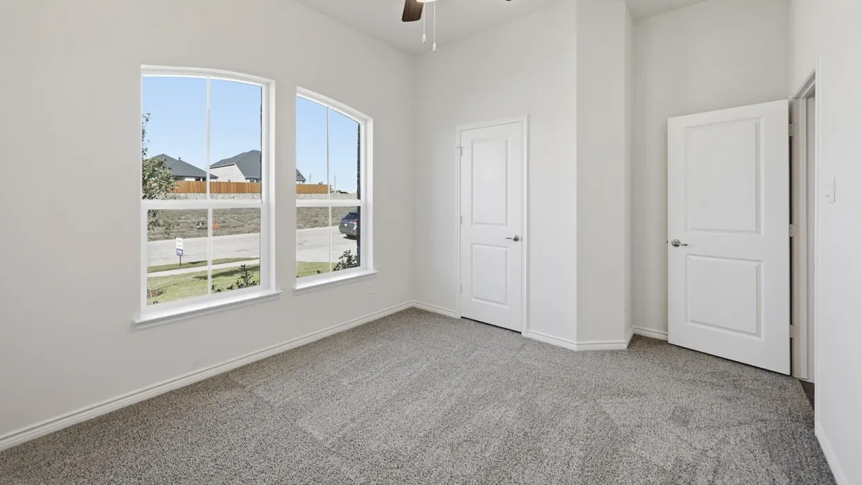 Carpeted room featuring two arched windows, two panel doors, and a ceiling fan