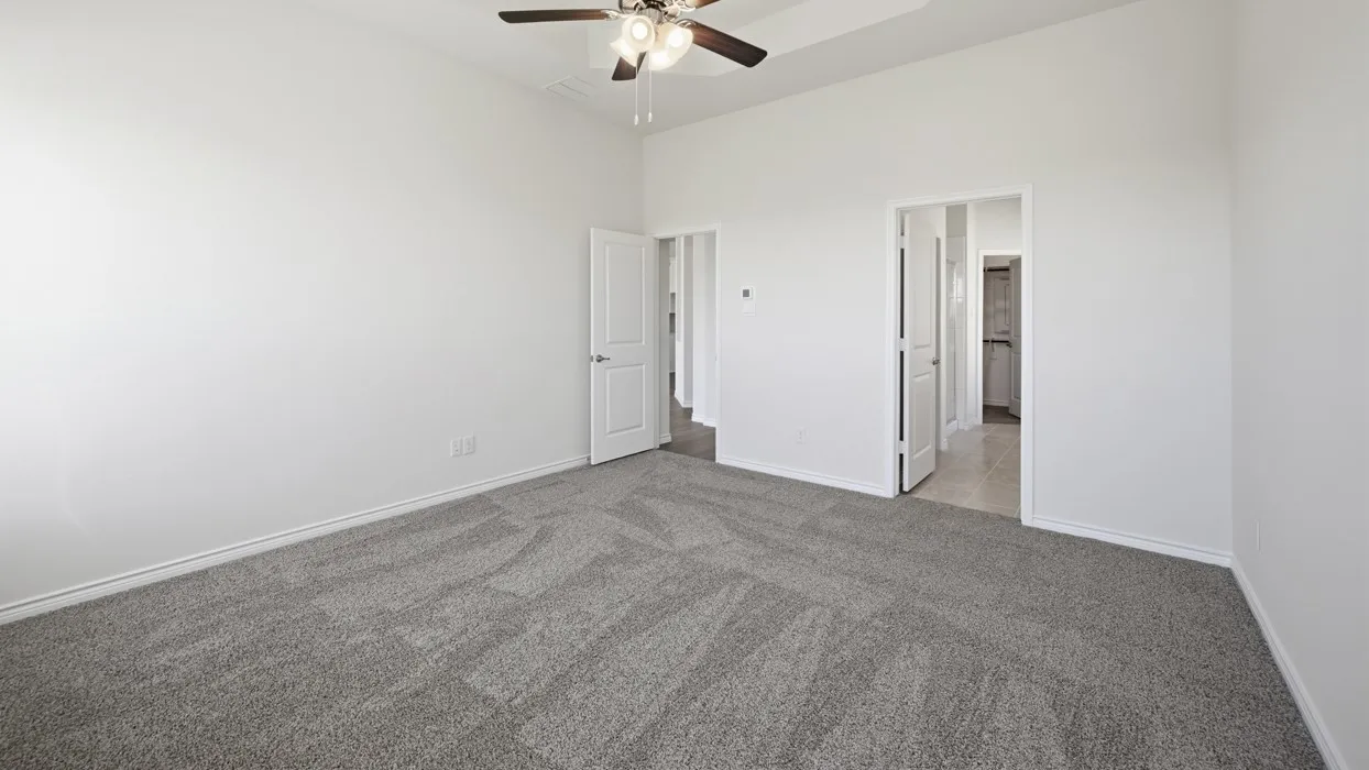Carpeted interior space featuring a ceiling fan, white trim, and two doorways