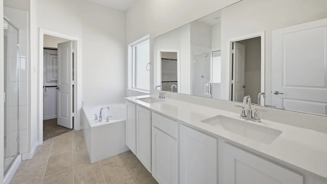 Bathroom featuring a double vanity with white cabinetry and integrated sinks, a built-in tub, an enclosed shower, and neutral tile flooring