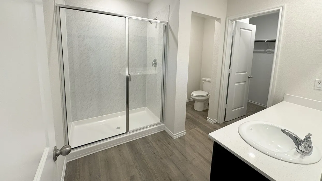 Bathroom featuring a glass-enclosed shower, white vanity with an undermount sink, quartz-finish countertop, and wood-finish flooring