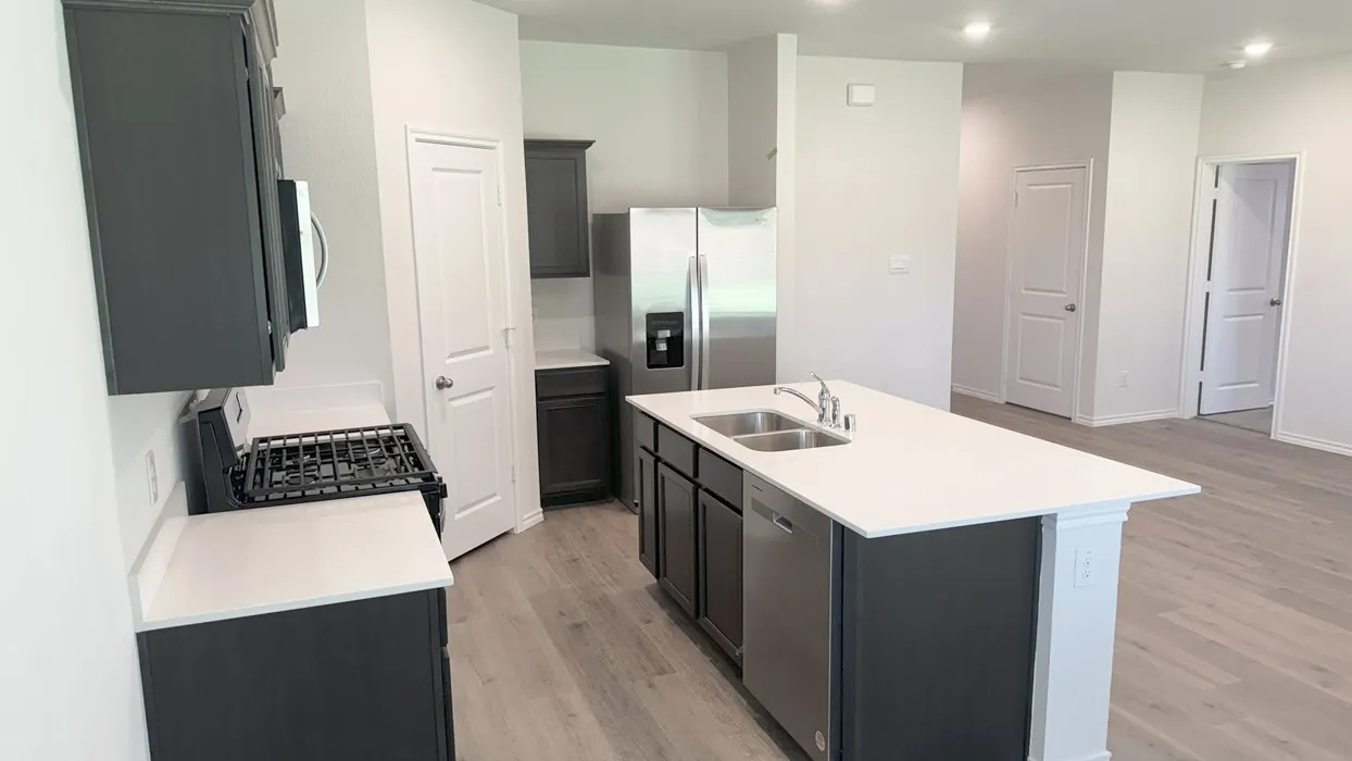 Modern kitchen featuring dark cabinetry, white countertops, stainless steel appliances, and wood-finish flooring
