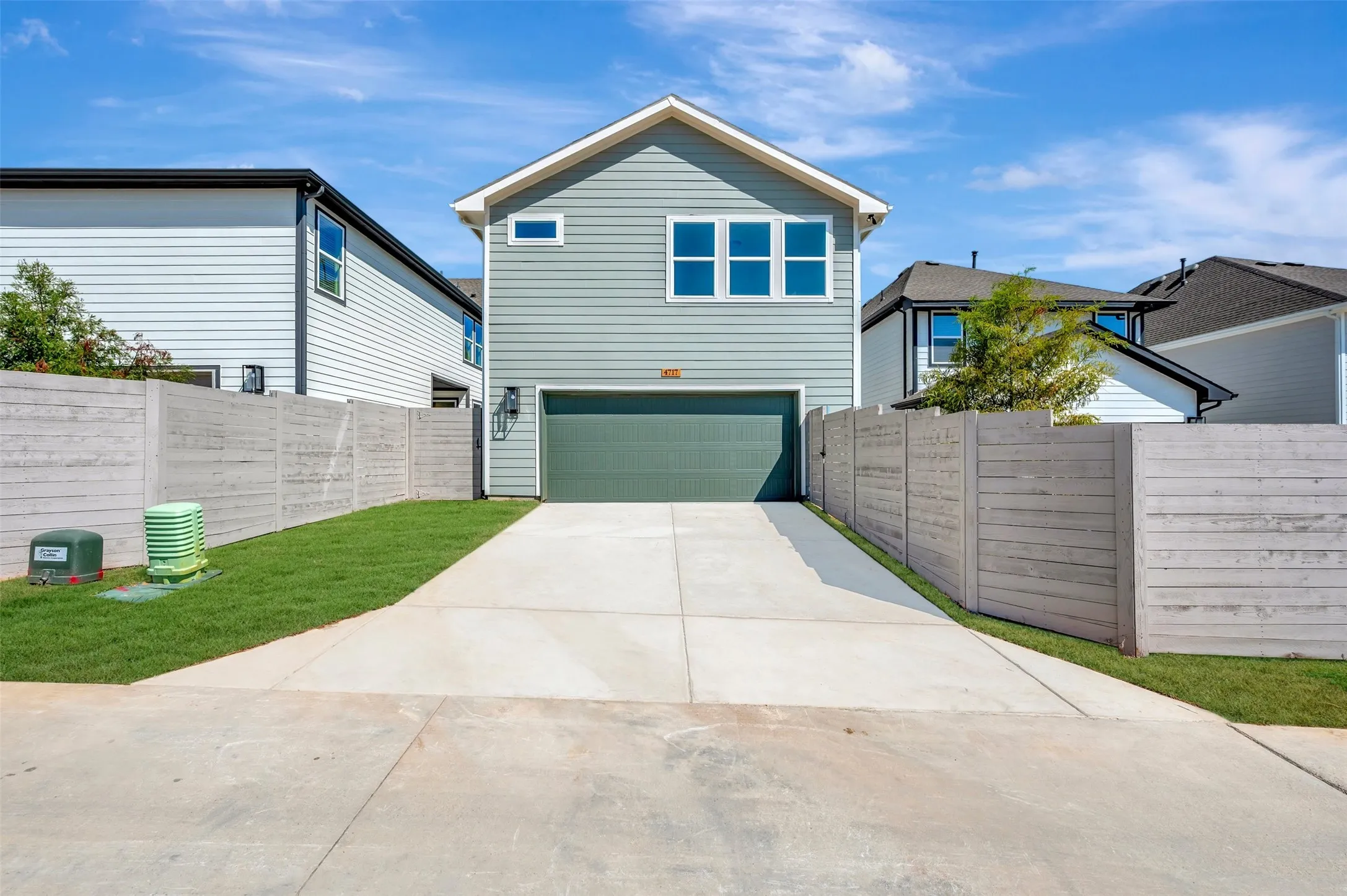 Two-story residence featuring horizontal siding, an attached garage, a concrete driveway, a manicured lawn, and a perimeter fence