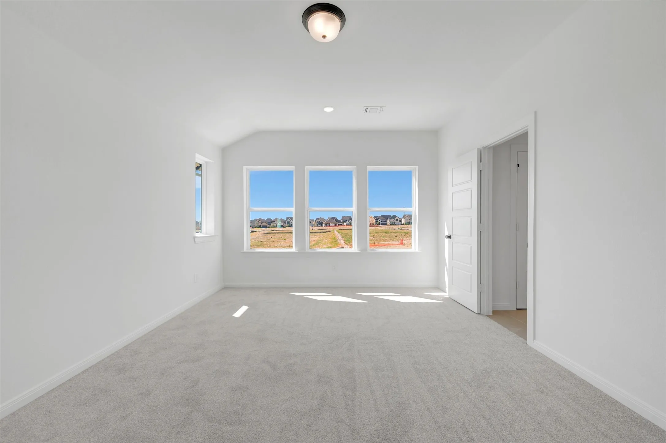 Spacious room featuring multiple windows, neutral carpeting, and a flush mount ceiling light