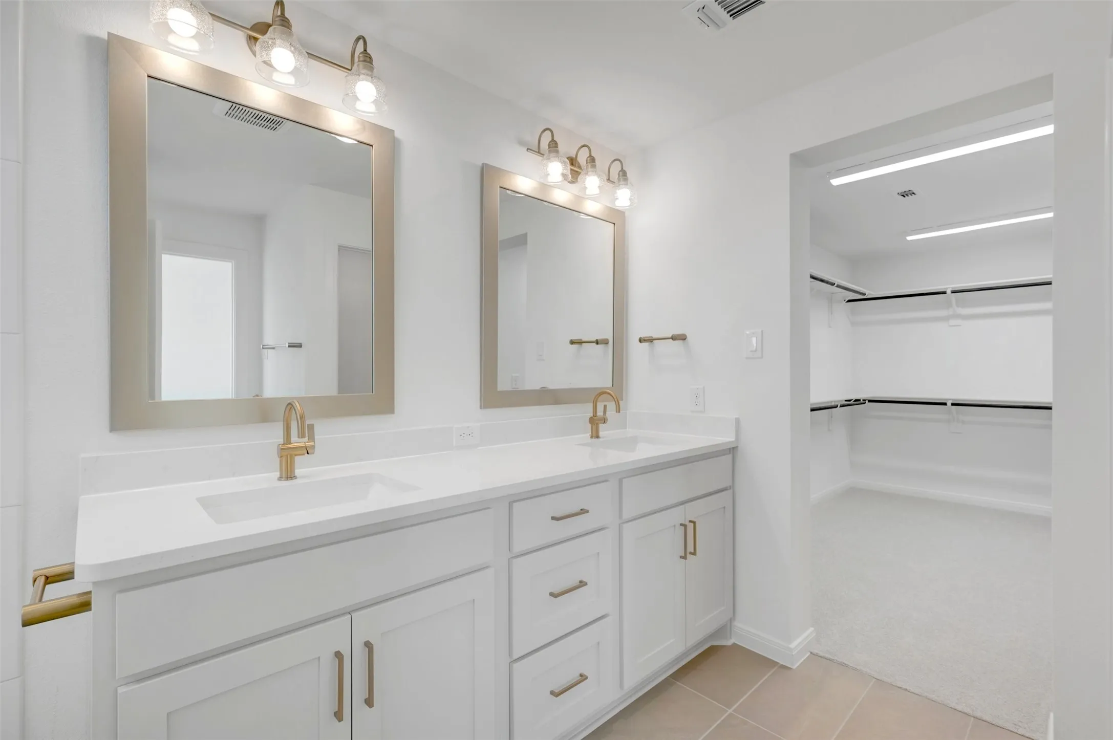 Dual vanity with white cabinetry and gold-tone hardware