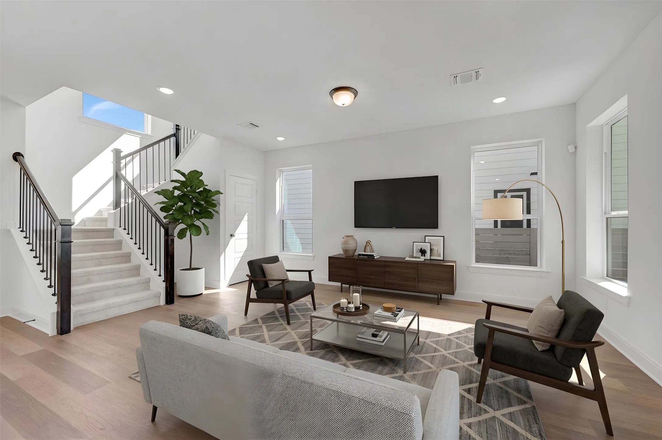 Hardwood-style flooring throughout, white walls, recessed lighting, double-pane windows, and a staircase with a black metal railing