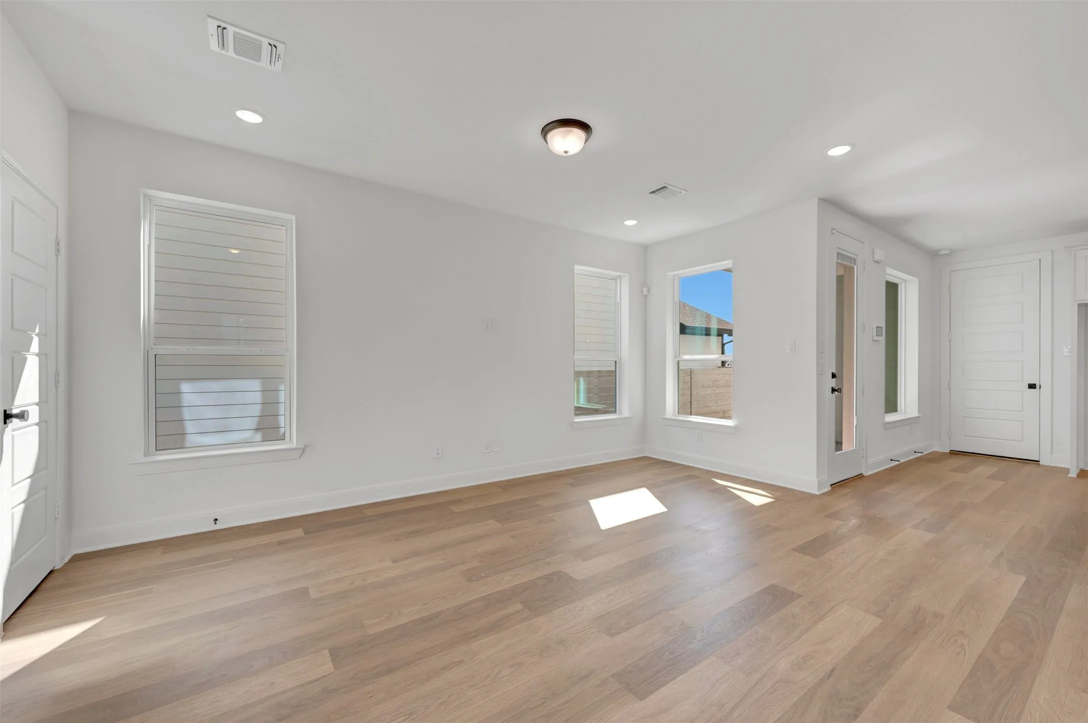 Bright interior with wood-finish flooring, recessed lighting, and multiple windows