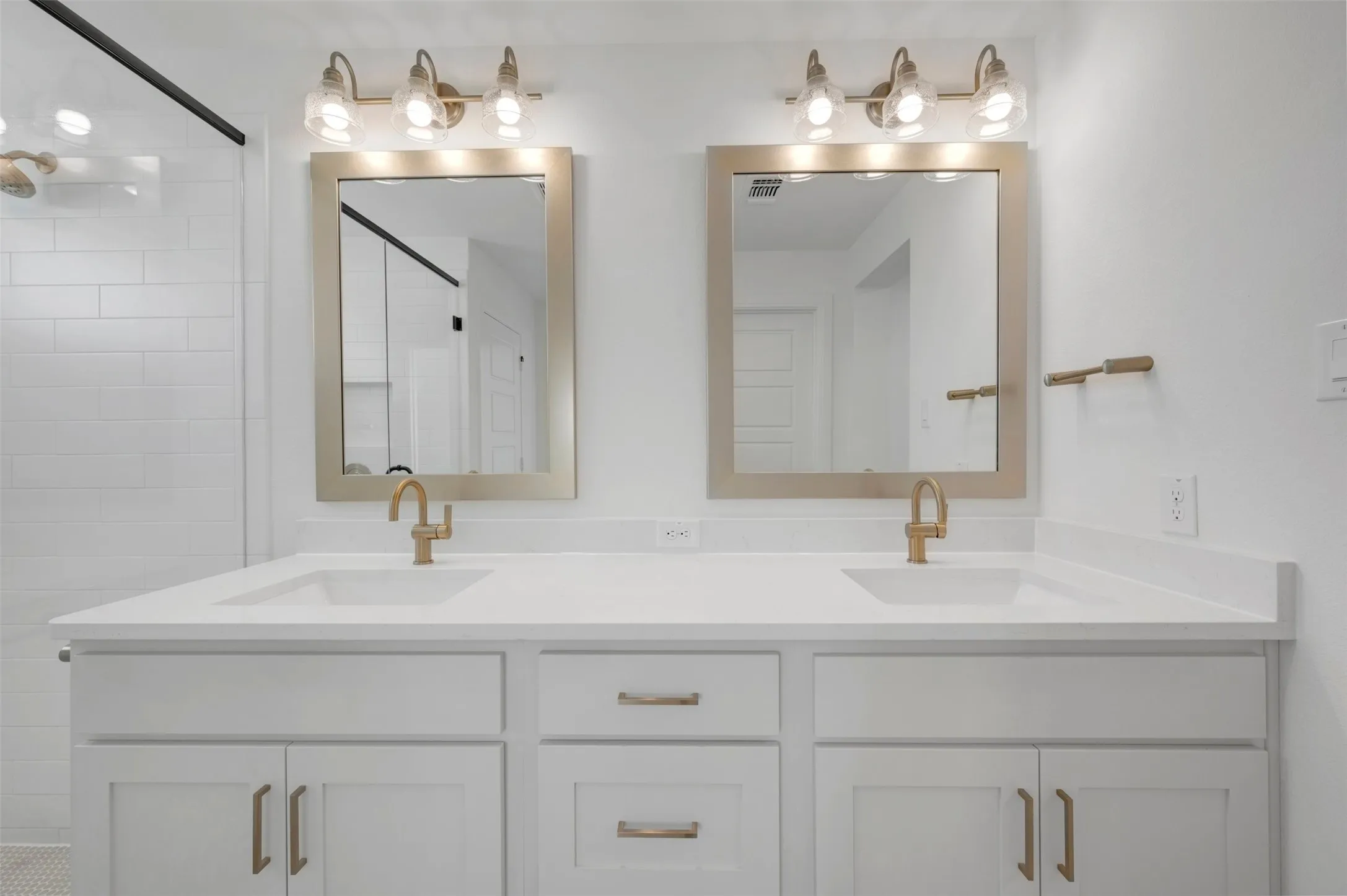 Dual vanity with white cabinetry, quartz countertops, and brushed gold fixtures