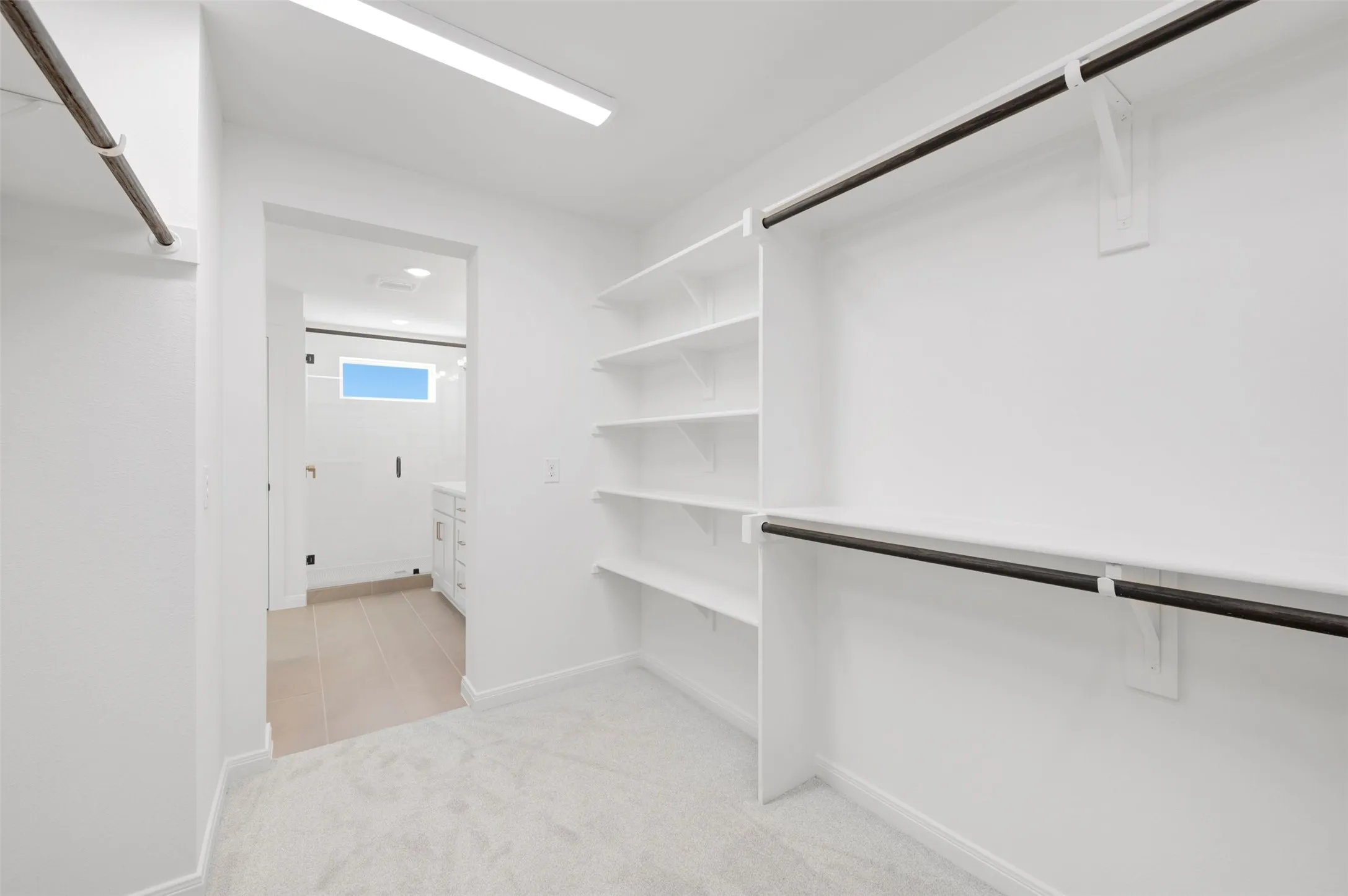 White built-in shelving, dual hanging rods, and light-colored carpeting