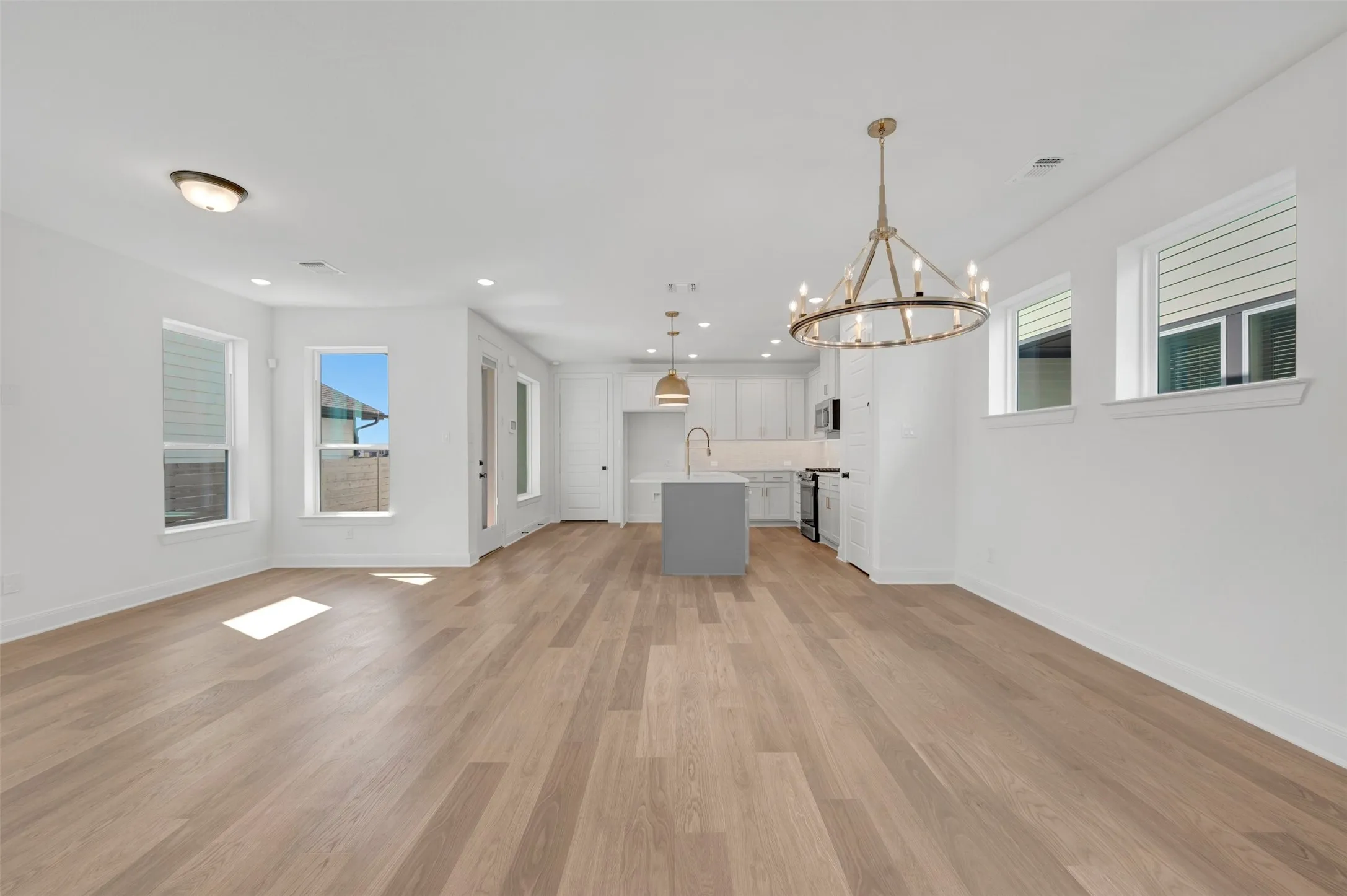 Expansive open-concept living space with wood-finish flooring, recessed lighting, and multiple windows