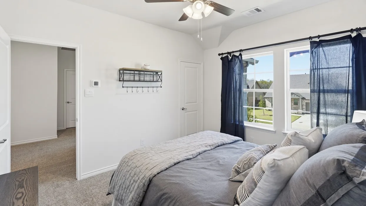 Carpeted room featuring a ceiling fan, vaulted ceiling, and dual windows