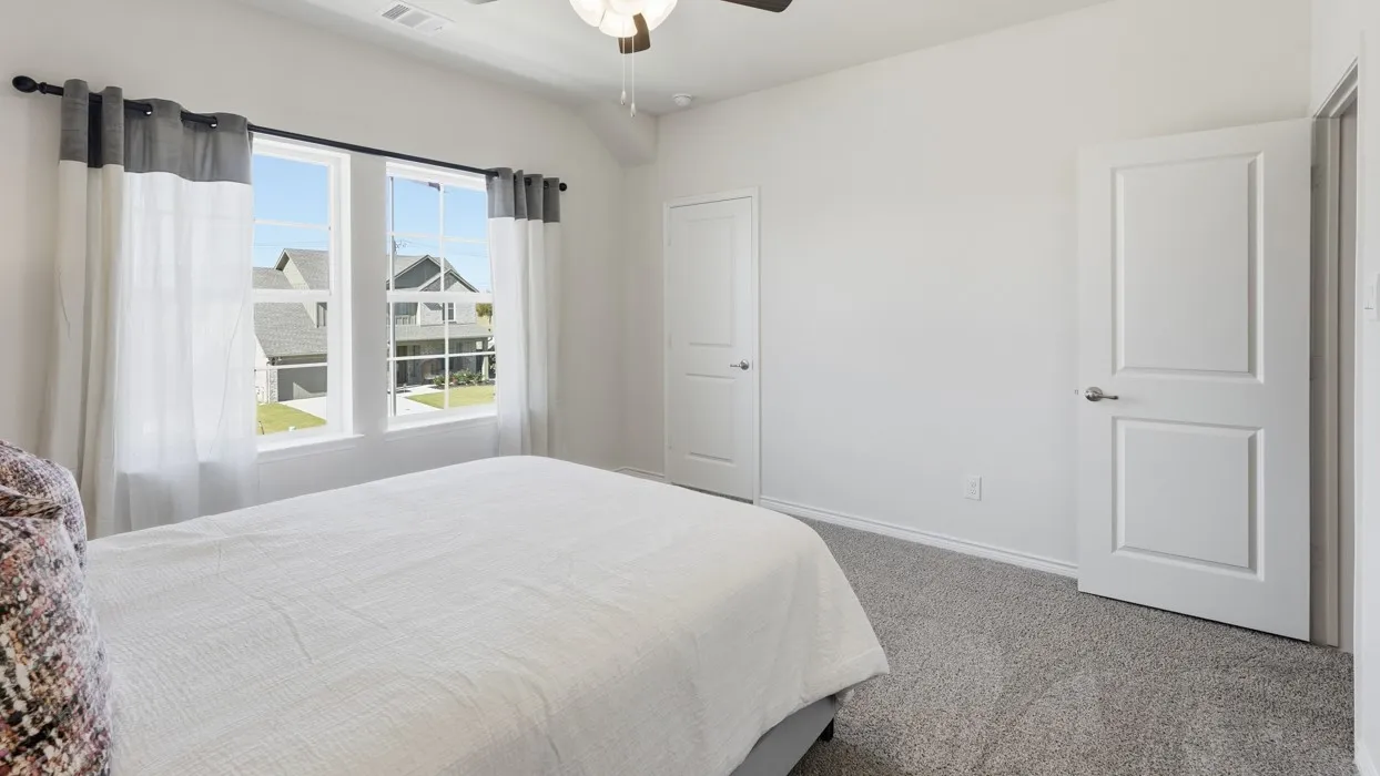 Spacious room with plush gray carpet, bright white walls, and a ceiling fan
