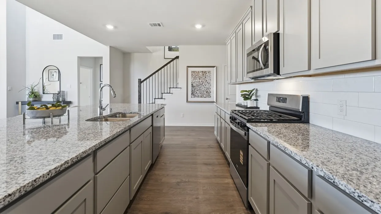 Modern kitchen featuring light gray cabinetry, stainless steel appliances, speckled countertops, a subway tile backsplash, and wood-finish flooring