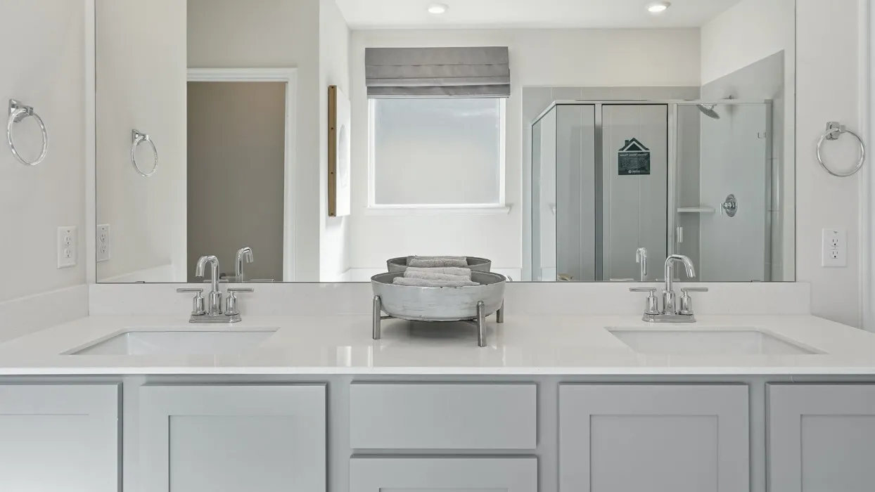 Double vanity with light gray shaker cabinetry and white countertops