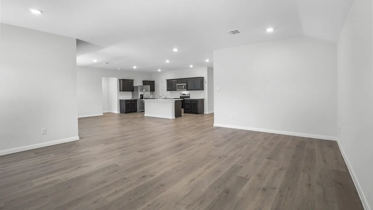 Open-concept living space featuring wood-finish flooring, recessed lighting, and a kitchen with dark cabinetry, light countertops, and a central island