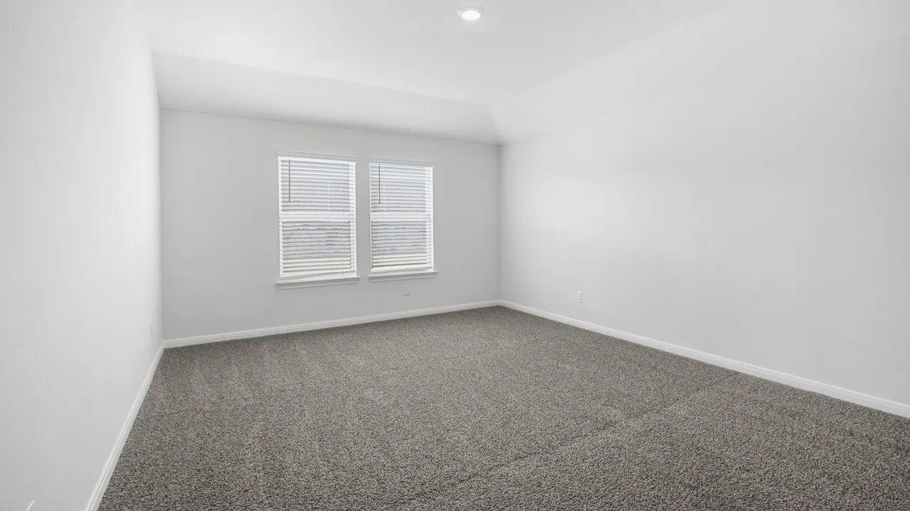Spacious room featuring gray carpet, white walls, and a vaulted ceiling with a recessed light fixture