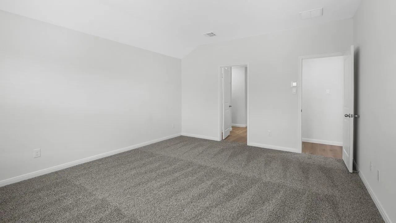 Spacious interior room featuring light gray carpeting, neutral wall finishes, white baseboards, and two doorways