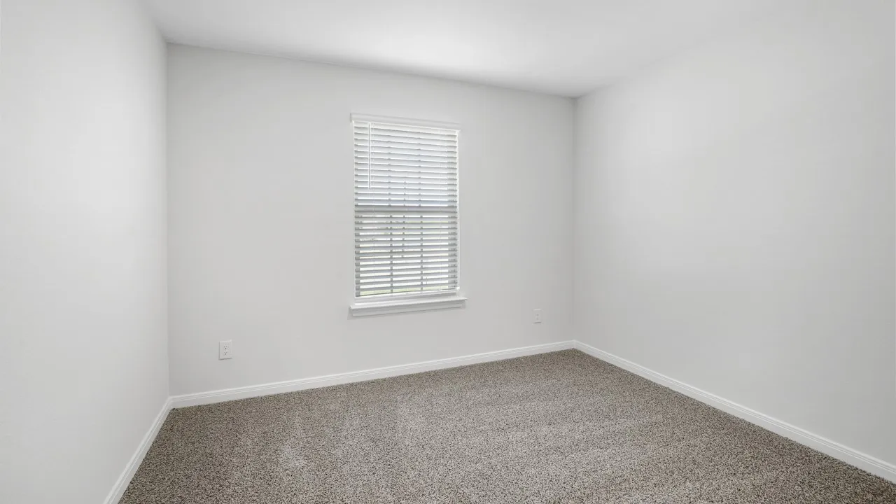 Neutral-toned carpeted room featuring a single window with blinds, white trim, and light-colored walls