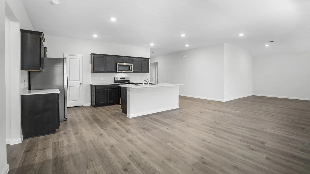 Open-concept living area featuring wood-finish flooring, recessed lighting, and a kitchen island with a double basin sink