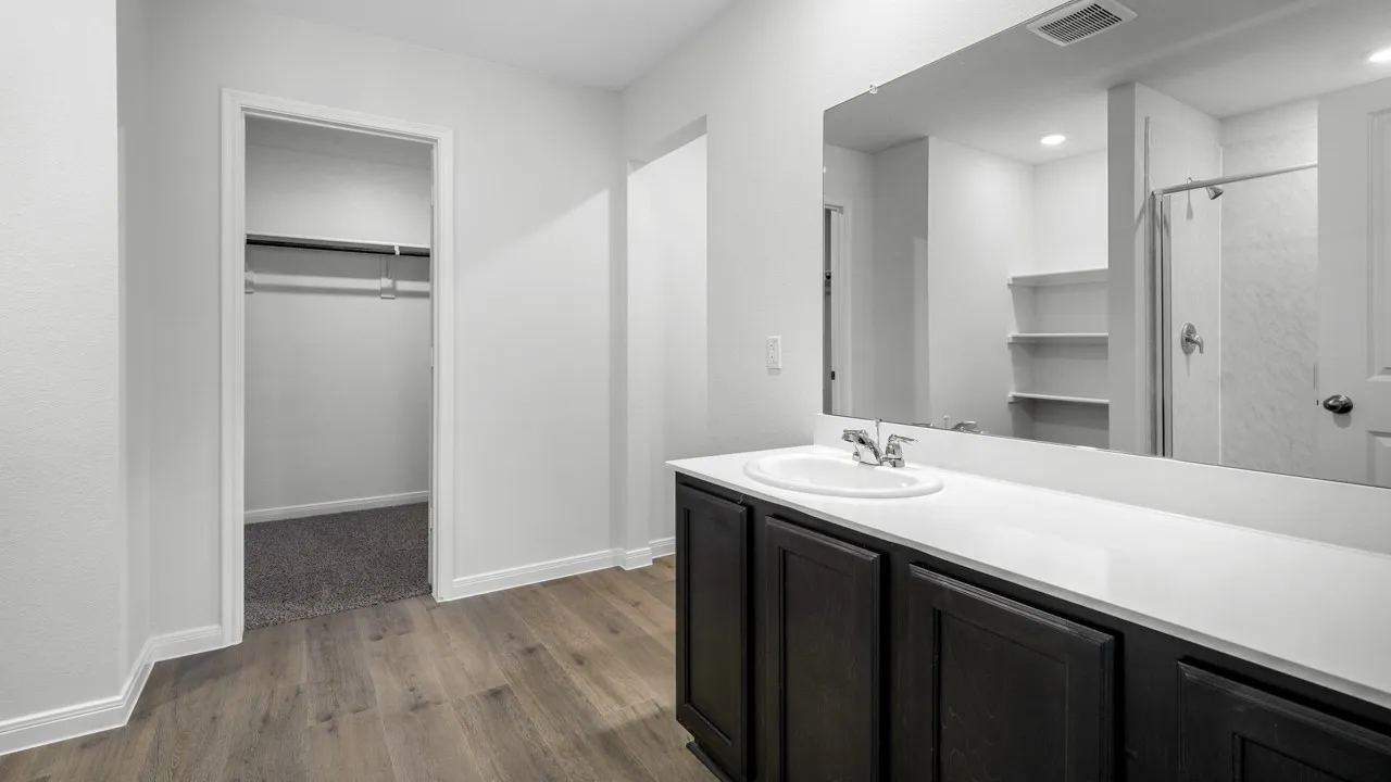 Bathroom vanity featuring a single basin sink, white countertop, and dark wood-finish cabinetry
