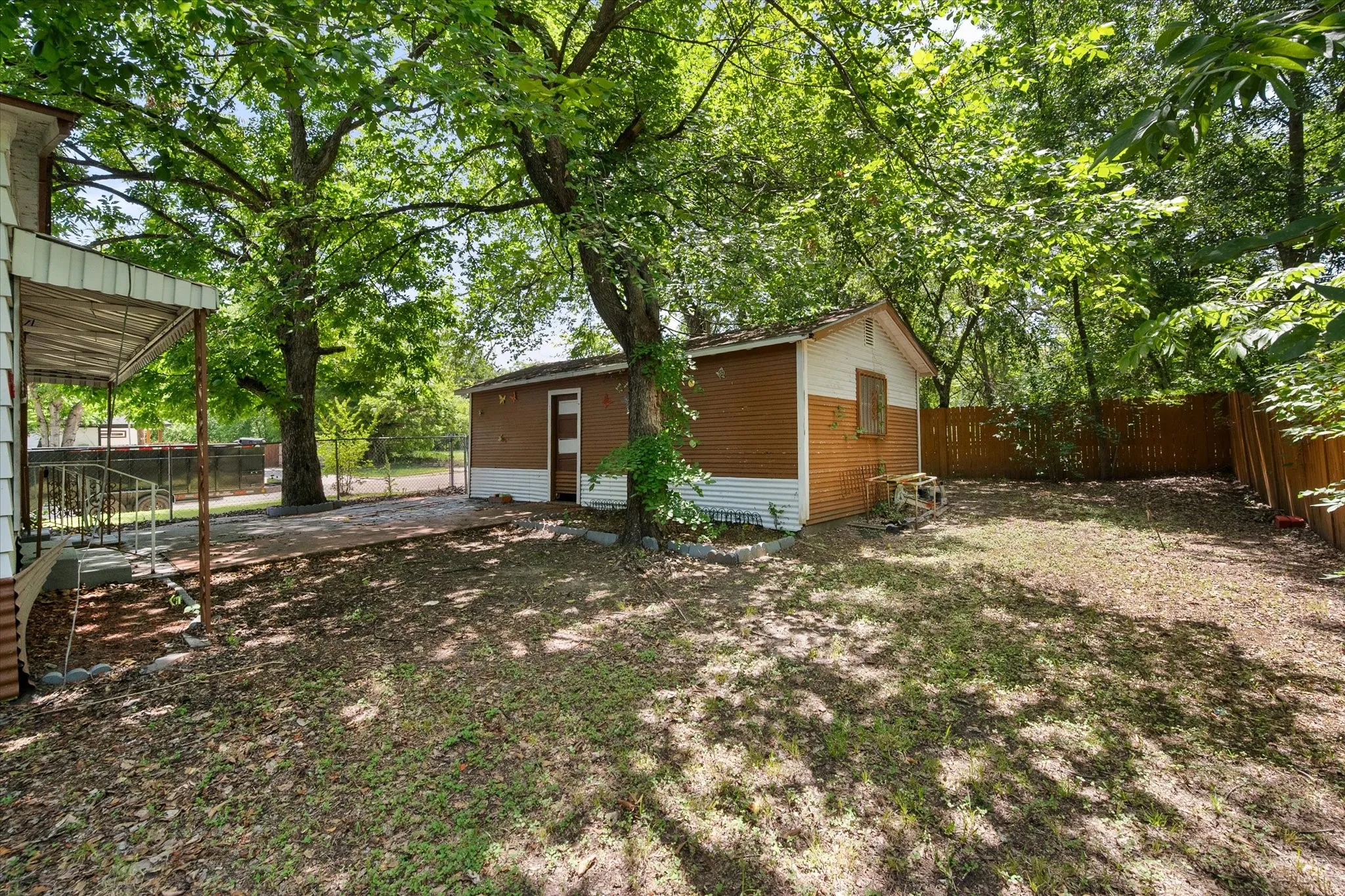 The fenced backyard includes mature trees and access to the detached garage, creating room for storage, projects, or outdoor improvements.