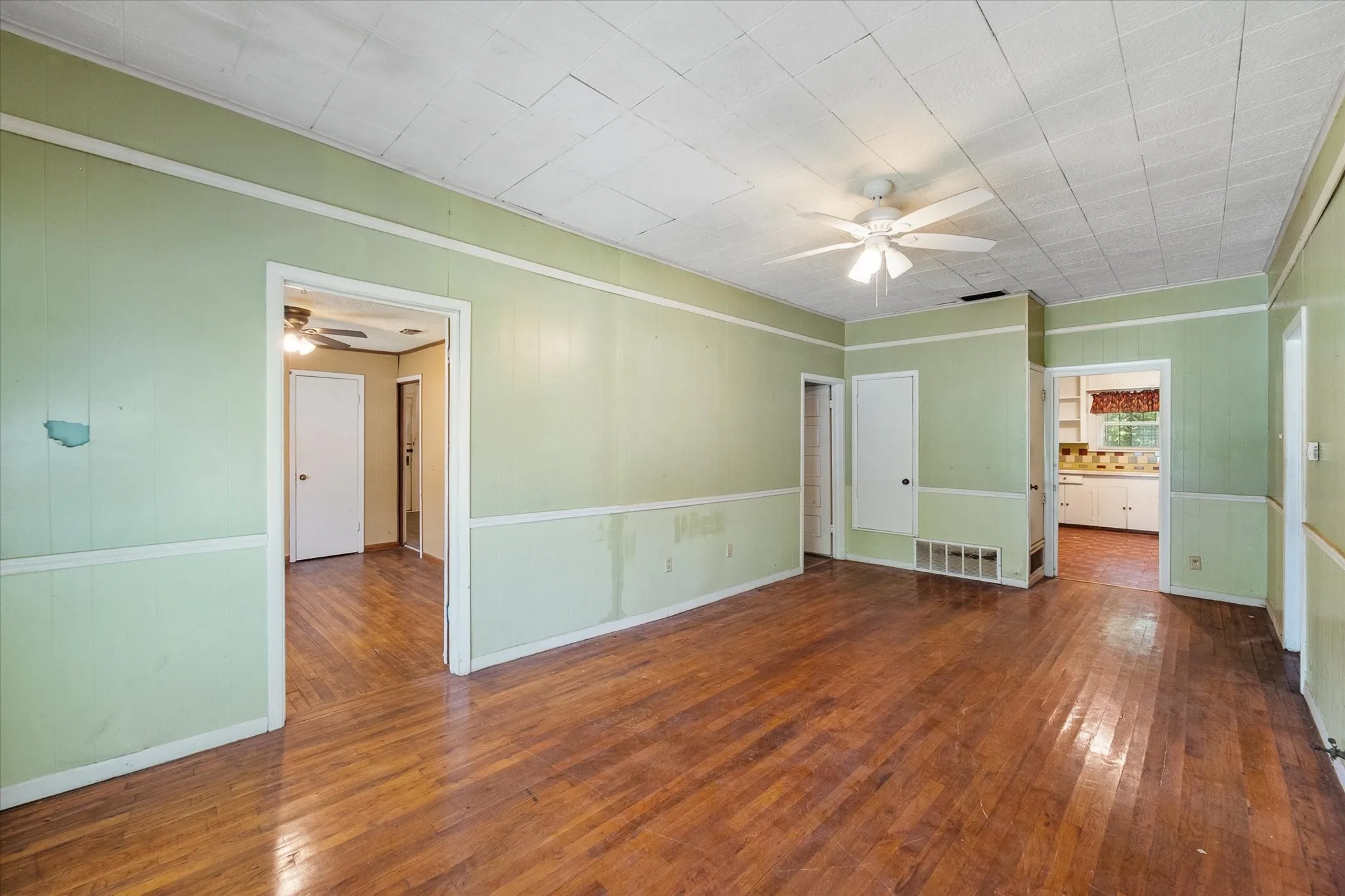 The approximately 11-by-23 living room features hardwood flooring, a ceiling fan, and abundant space for multiple furniture zones