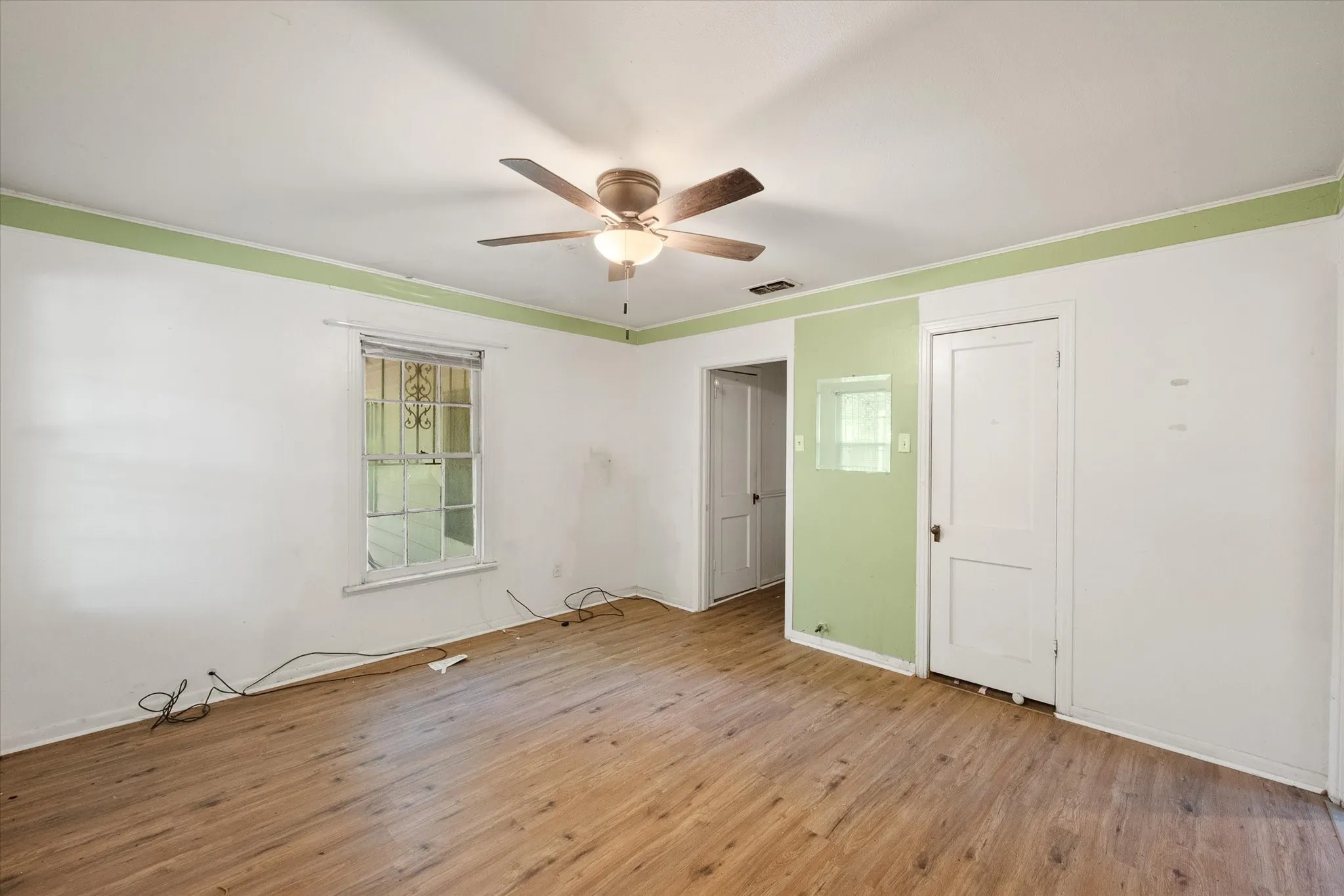A generously sized bedroom includes a ceiling fan, natural light, and convenient closet storage.