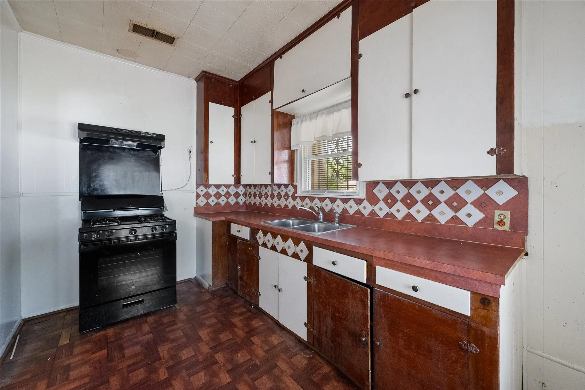 The kitchen includes a gas range, double-basin sink, built-in cabinetry, and plentiful workspace for future updates.