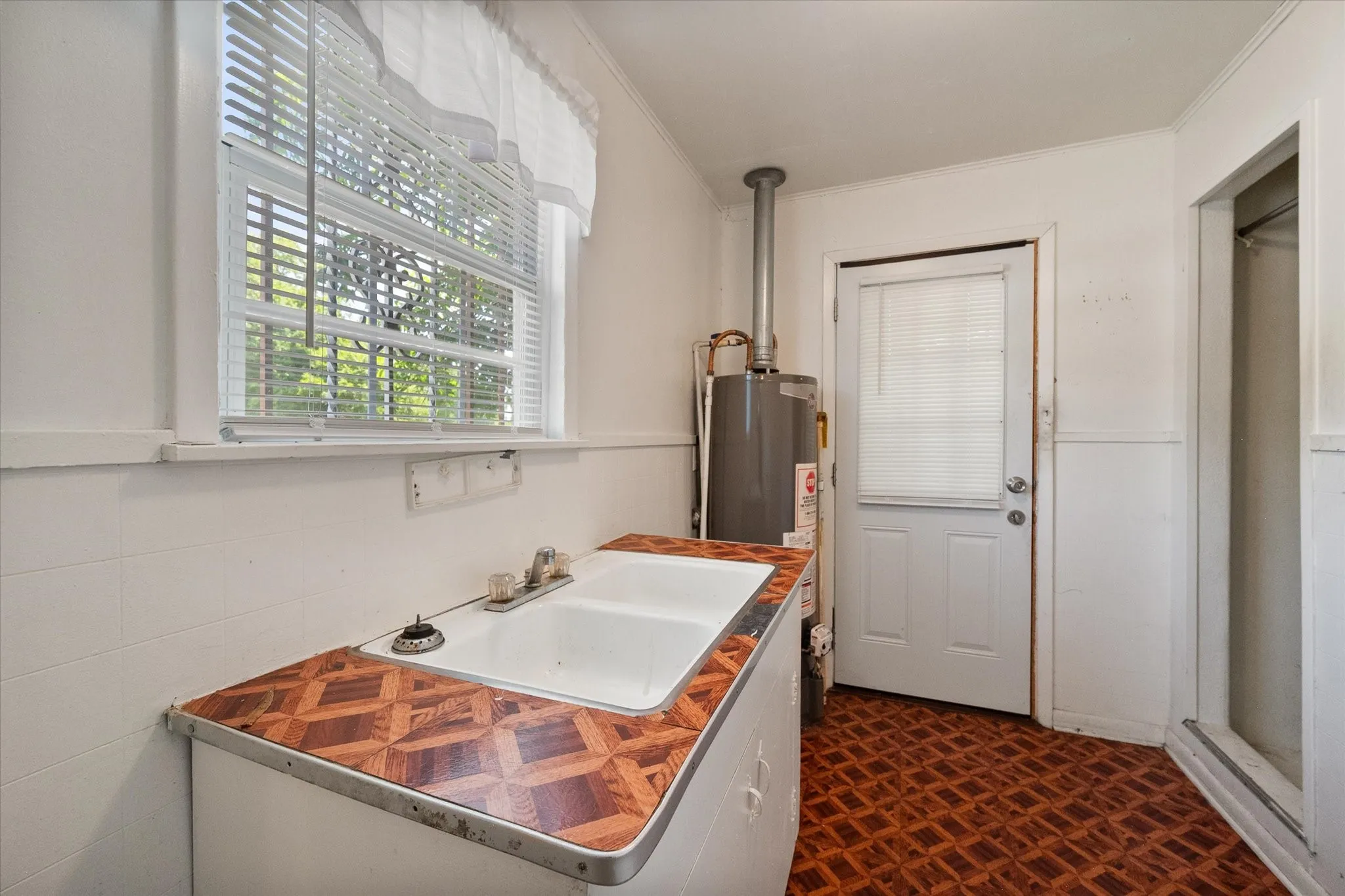 Separate utility room includes a sink, built-in cabinetry, natural light, and access to the exterior.