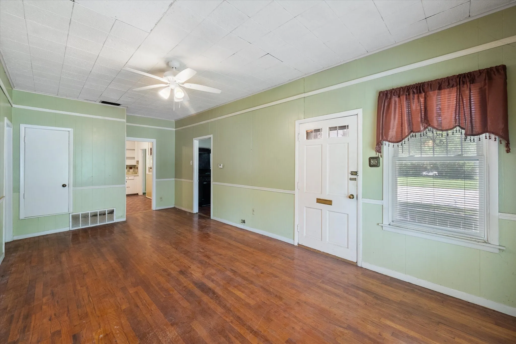 Front living room offers hardwood flooring, a ceiling fan, and direct access from the covered porch.