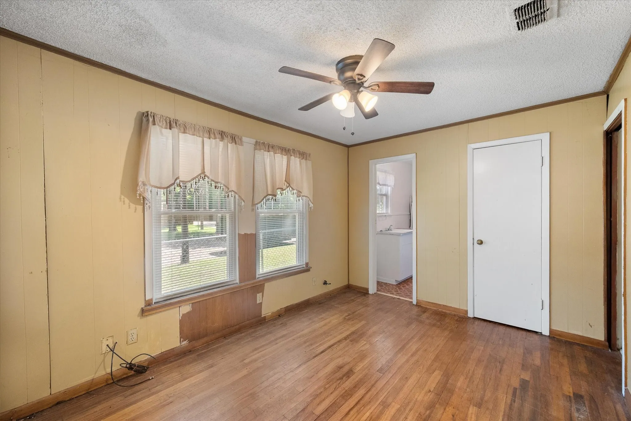 This 13-by-9 den features hardwood flooring, a ceiling fan, and connections to adjoining living spaces.