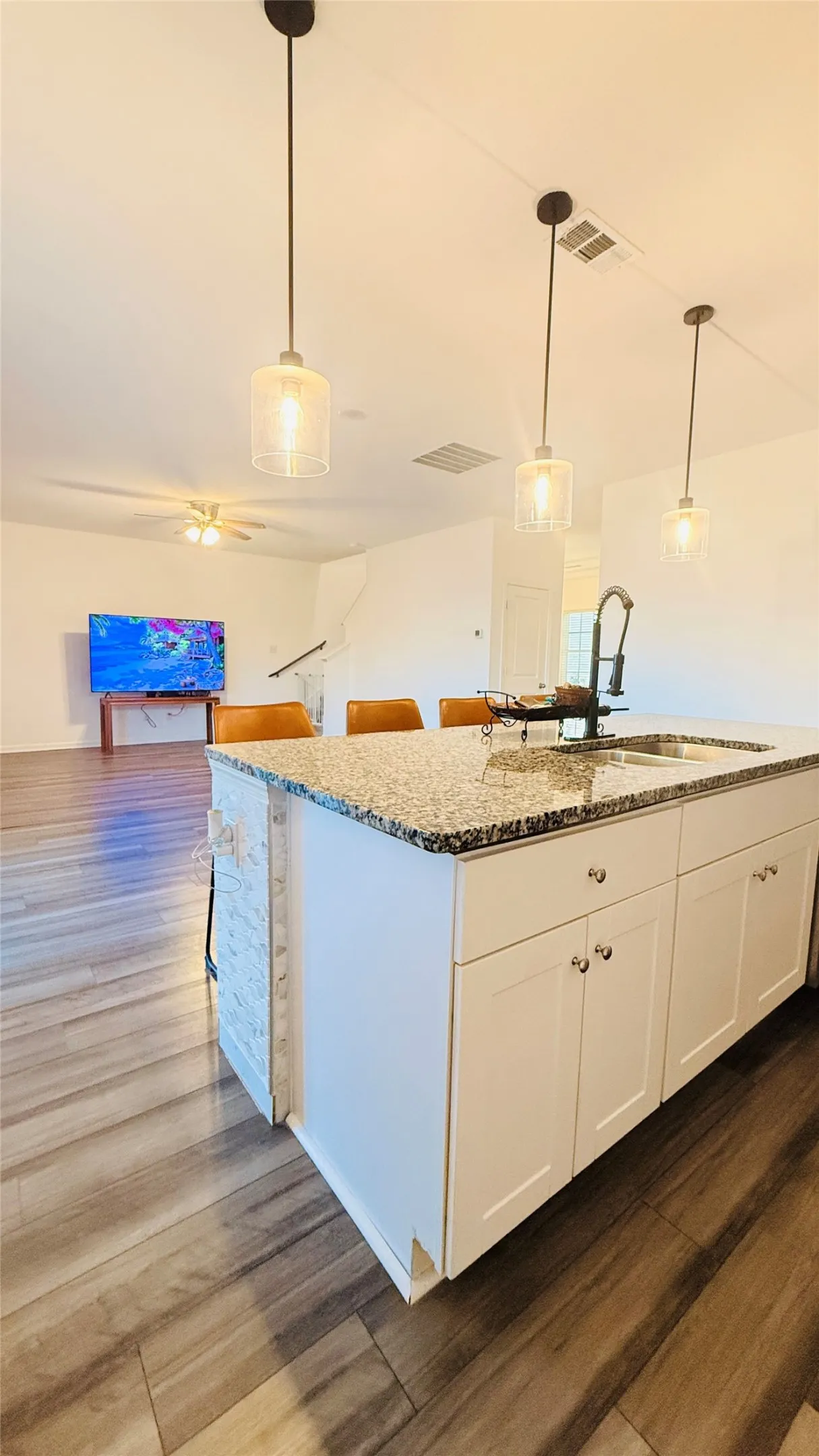 Kitchen island featuring white cabinetry, a speckled countertop, and an integrated sink with a gooseneck faucet