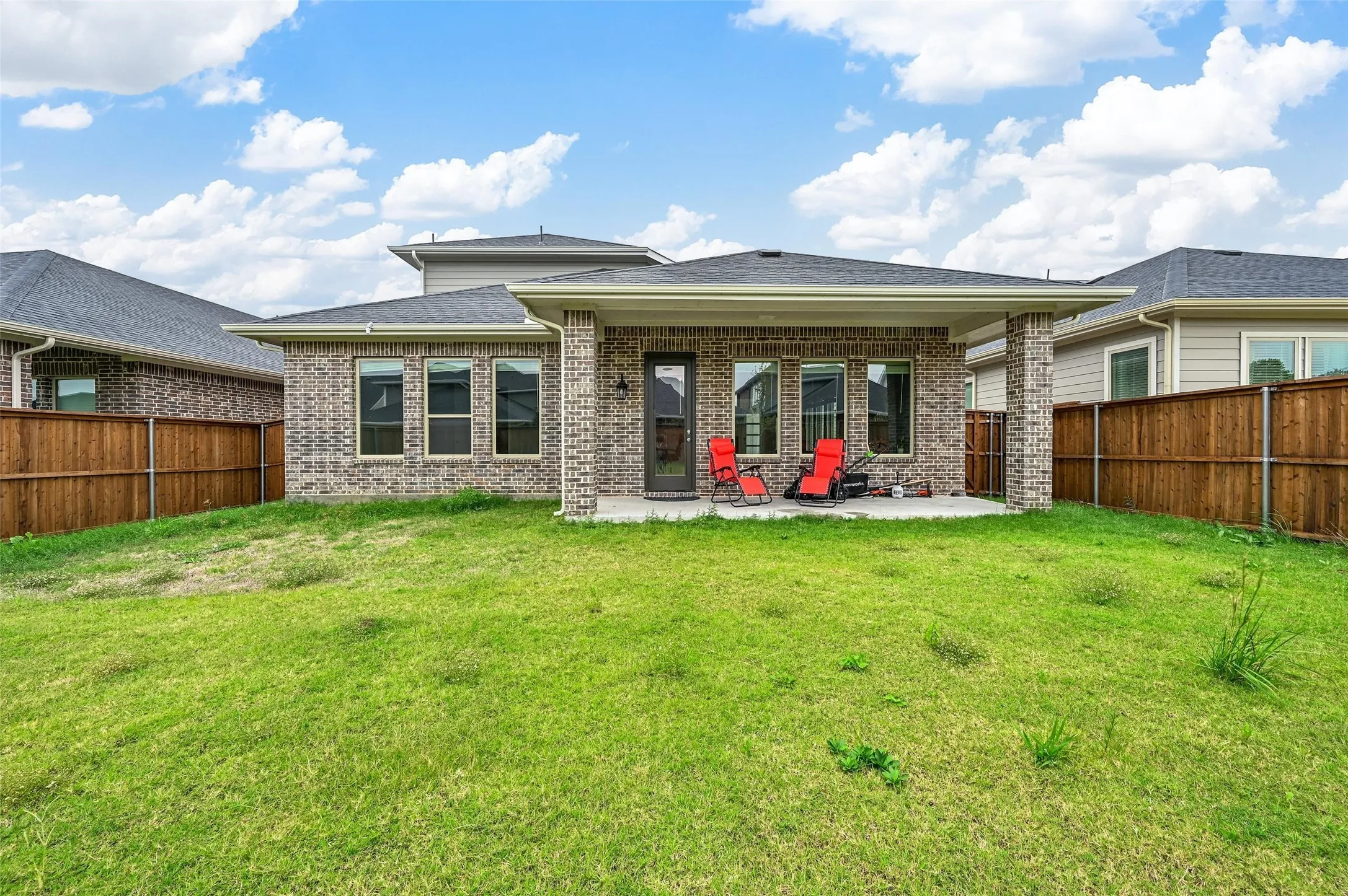 Back of house featuring a covered patio, brick siding, and a fenced backyard