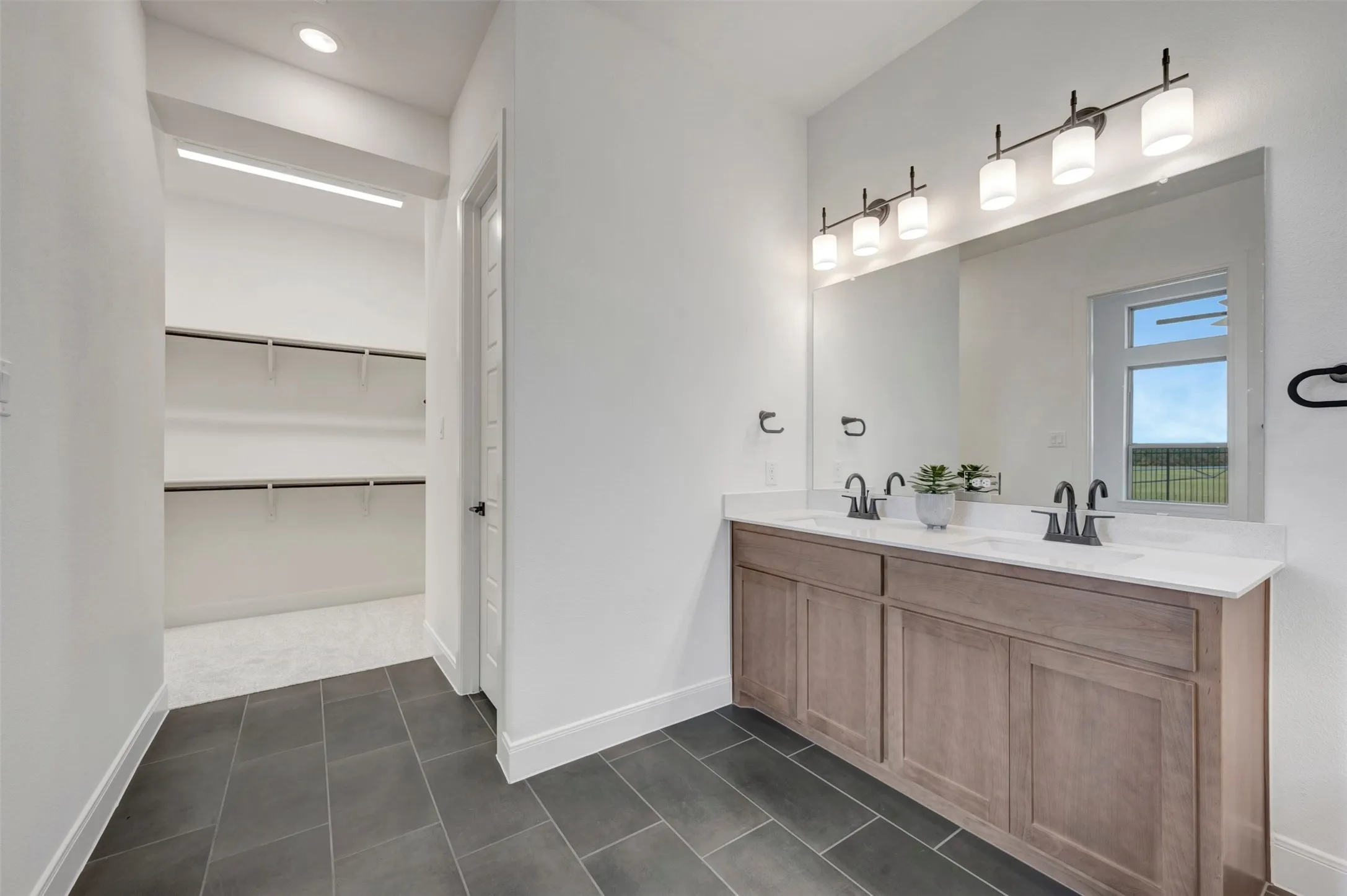 Dual vanity with wood-finish cabinetry, white countertop, and matte black fixtures