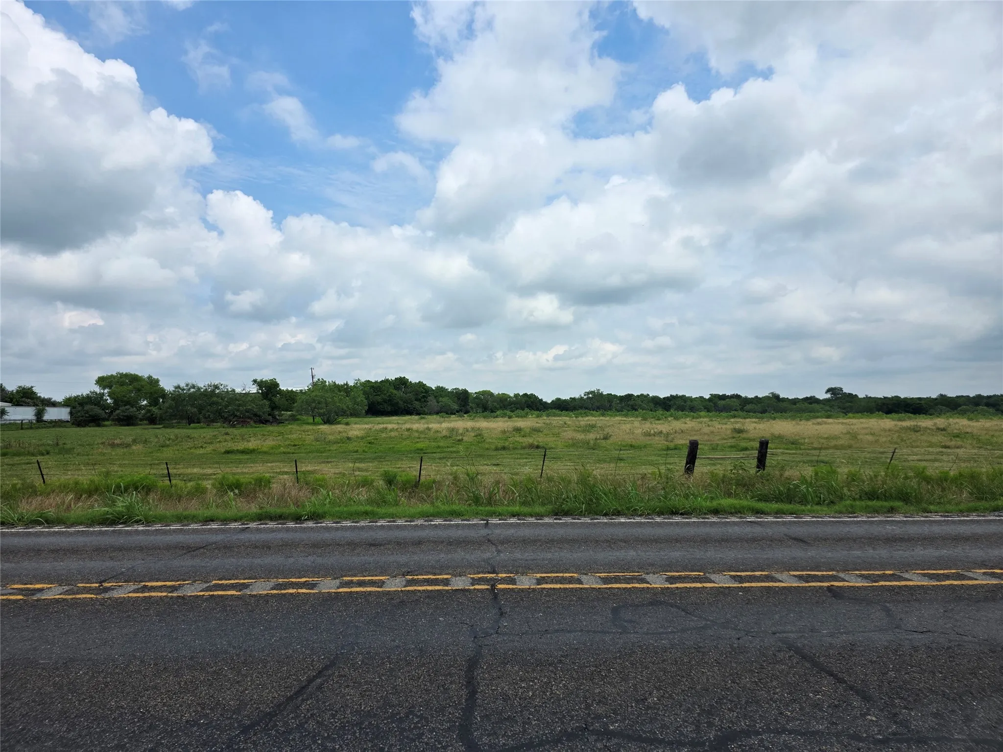 Road frontage with a grassy expanse and distant trees