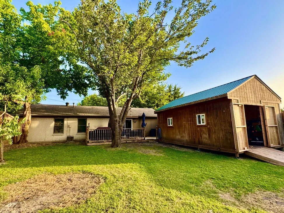 Expansive backyard featuring a detached storage building with a metal roof and a wood-finish exterior