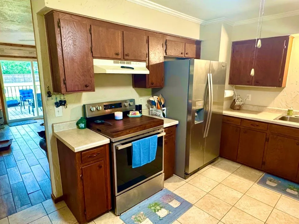 Kitchen featuring wood-finish cabinetry, stainless steel appliances, and a tile floor