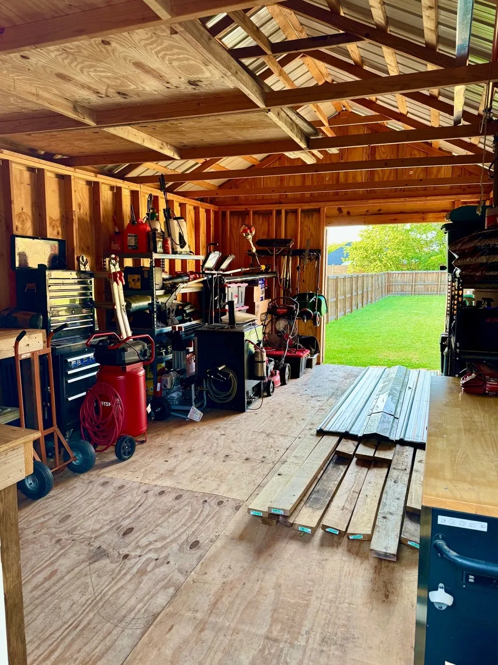 Spacious outbuilding with exposed wood framing, plywood flooring, and a metal roof structure