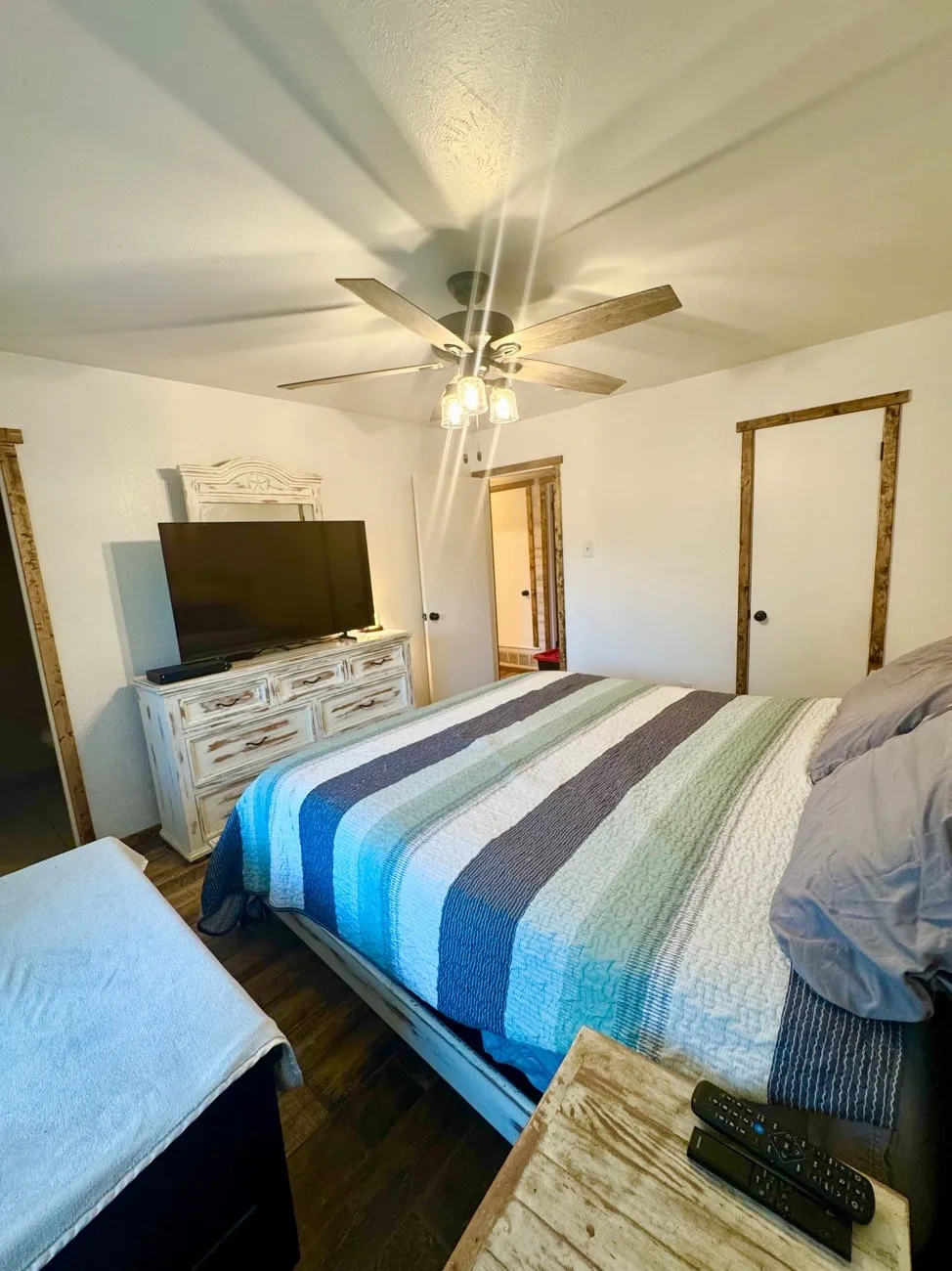 Spacious room featuring wood-finish flooring, a ceiling fan with integrated lighting, and white walls