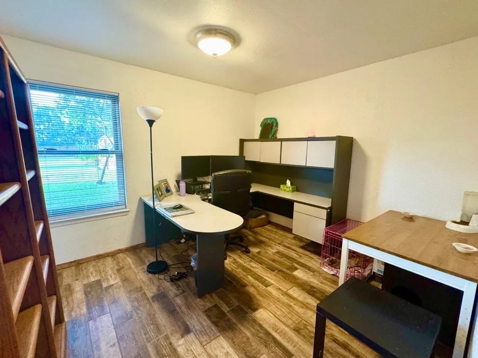 Room featuring wood-finish flooring, a window with horizontal blinds, and a built-in overhead light fixture