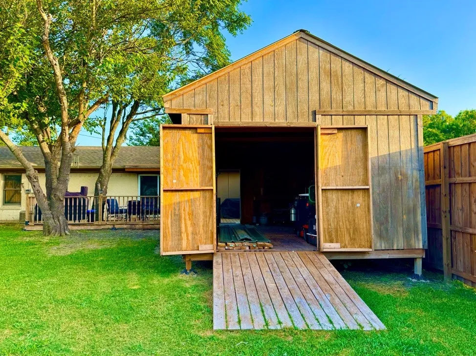 Rear yard featuring a wood-sided outbuilding with sliding barn doors and a wood ramp