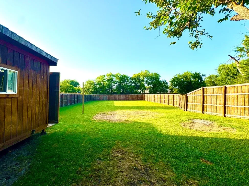 Expansive grassy yard with a full privacy fence