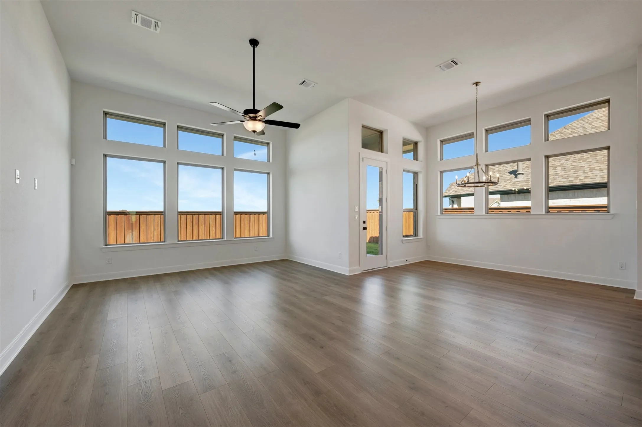 Expansive living area featuring wood-finish flooring, high ceilings, and abundant window placements