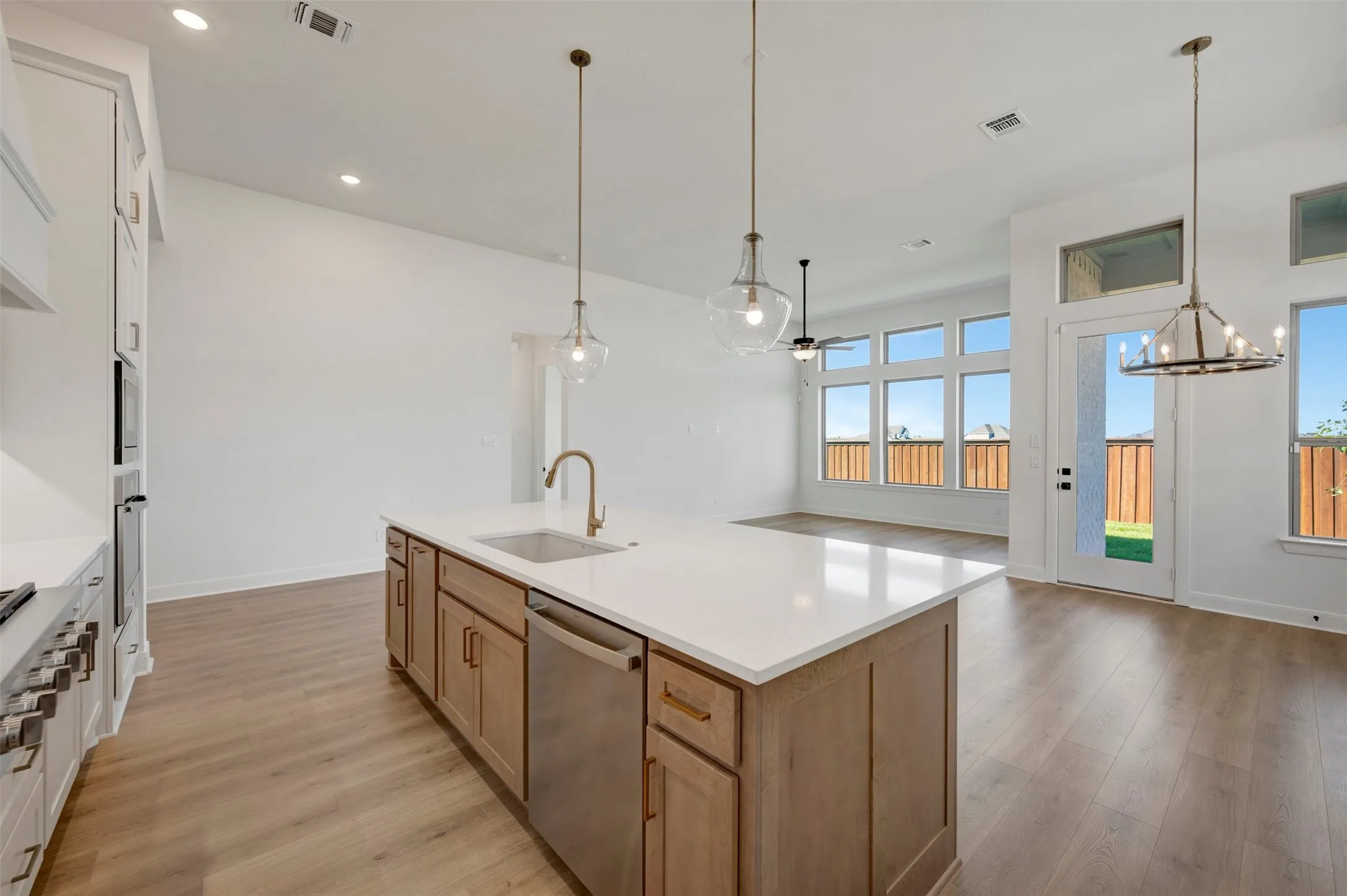 Kitchen island with a built-in sink and stainless steel dishwasher, illuminated by pendant lighting